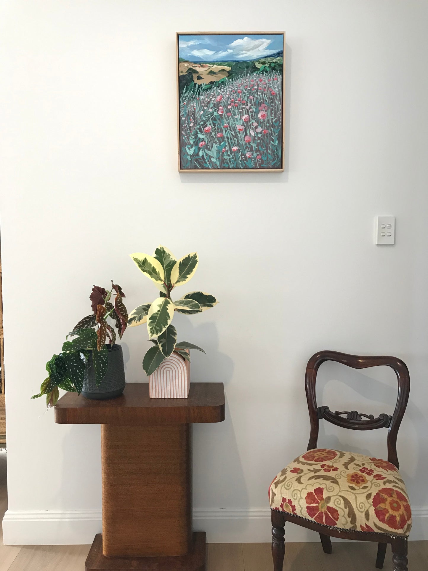 Room interior with a chair, table, and wall art.