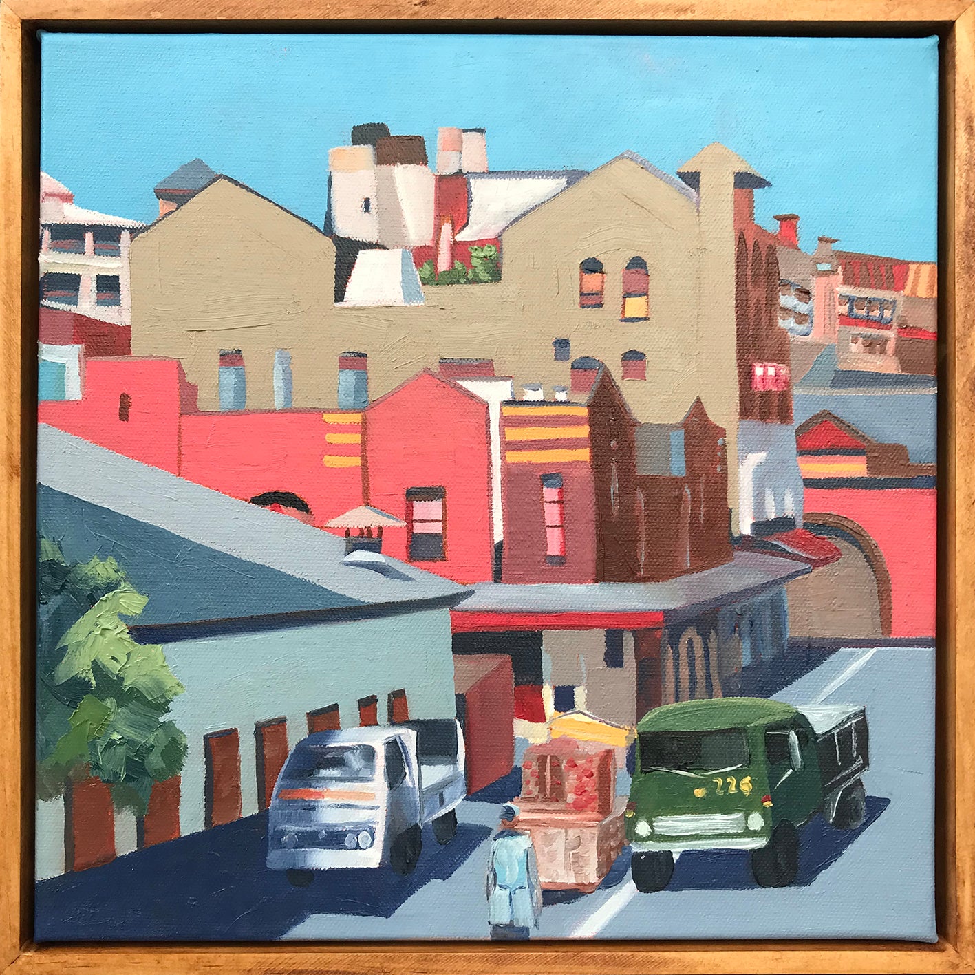 Painting of a city street with buildings and vehicles, framed in wood.