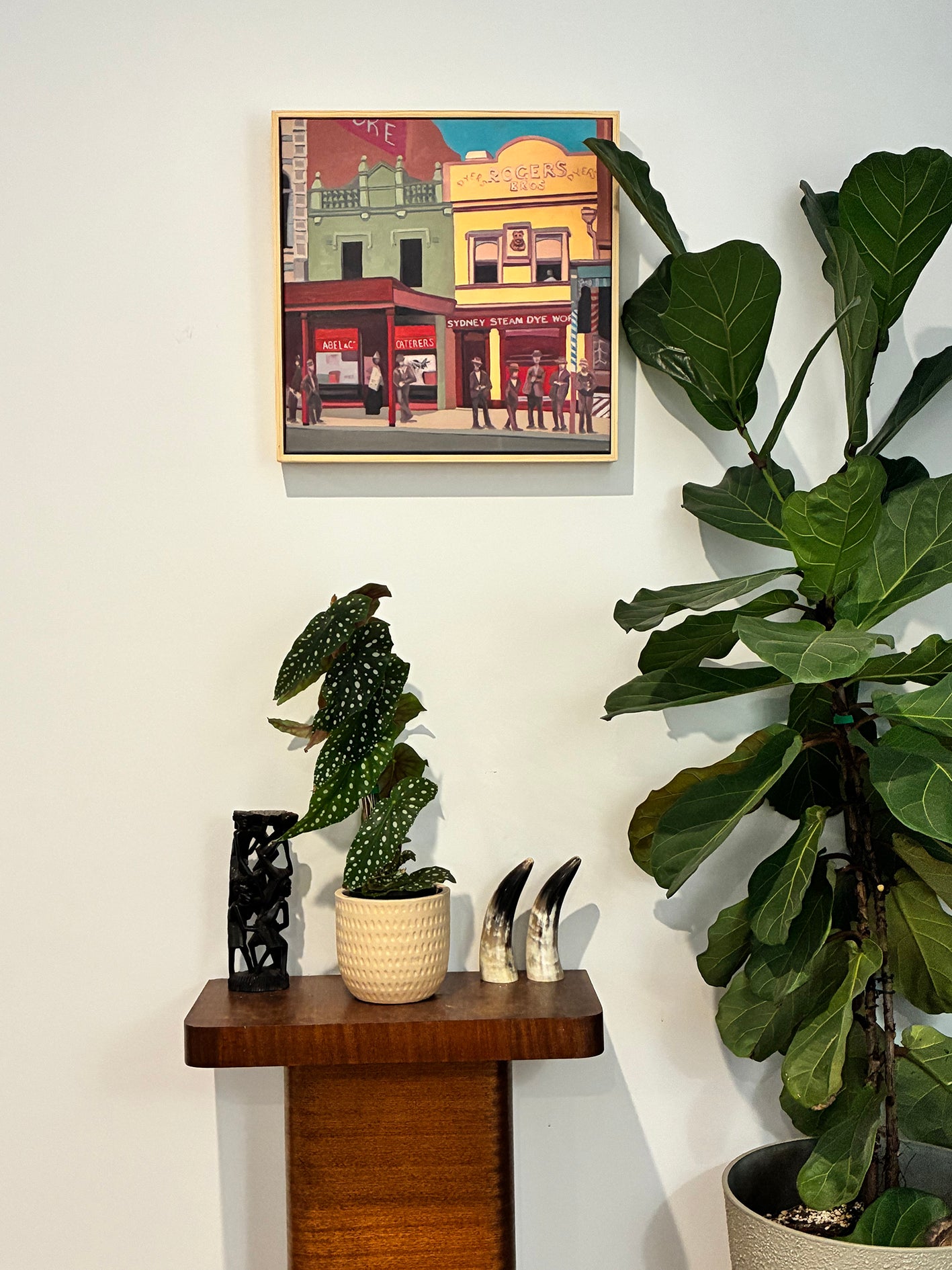 Decorative setup with plants and a framed picture on a wall.